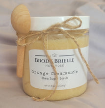 Load image into Gallery viewer, Jar of Brody Brielle Orange Creamsicle Shea Sugar Scrub with a wooden spoon on a neutral background