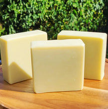 Load image into Gallery viewer, Three bars of soap on a wooden surface with a green outdoor background
