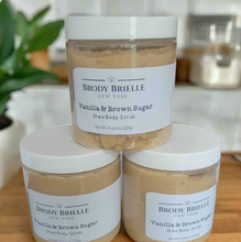 Load image into Gallery viewer, Three jars of Brody Brielle Vanilla &amp; Brown Sugar Shea Body Scrub stacked on a wooden surface.
